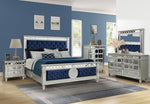 Luxury bedroom set with blue and silver furniture in a room with blue walls.